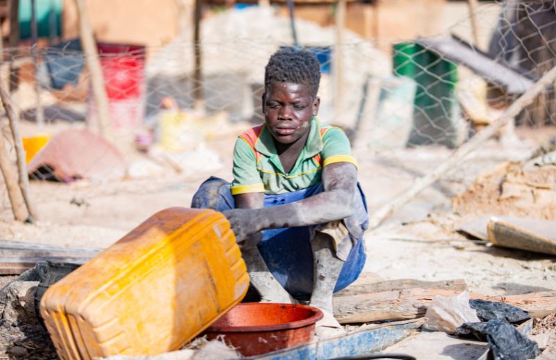 Above Covered in dust and working alone, a child labours at a gold mining site.